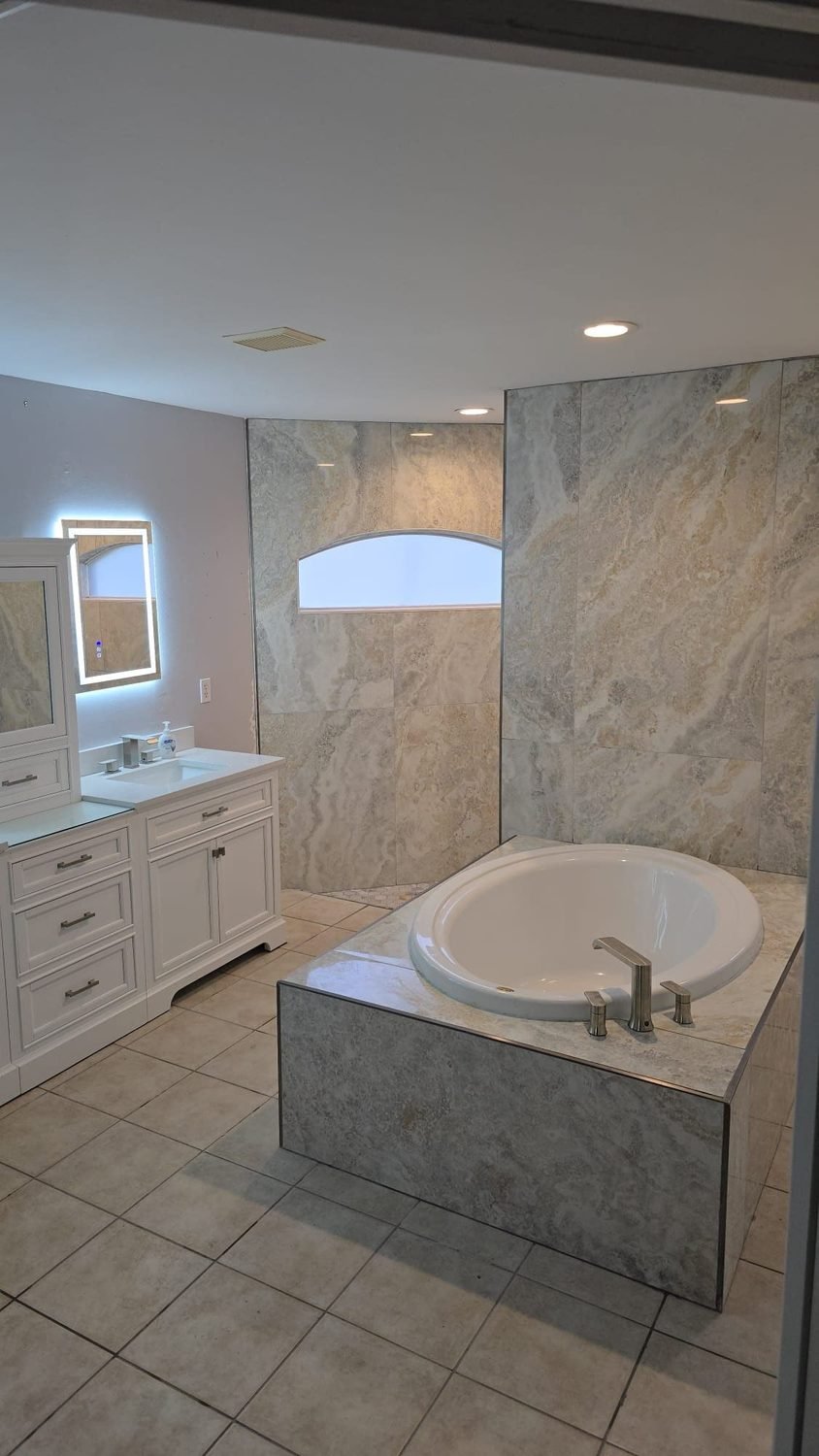 Master bathroom renovation with soaking tub and stone tile by Carter Elite Renovations