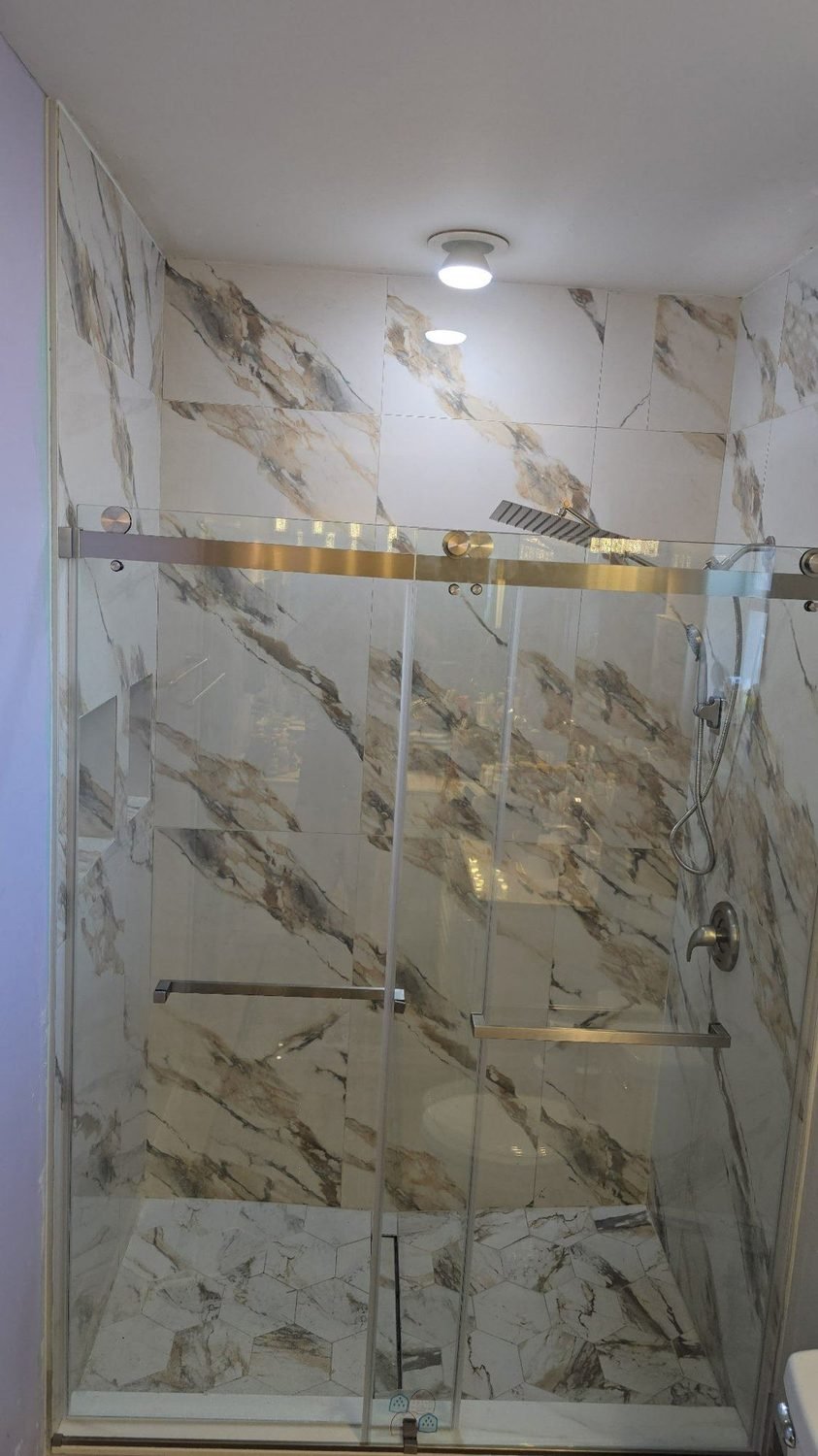 Walk-in shower with marble tile and glass enclosure